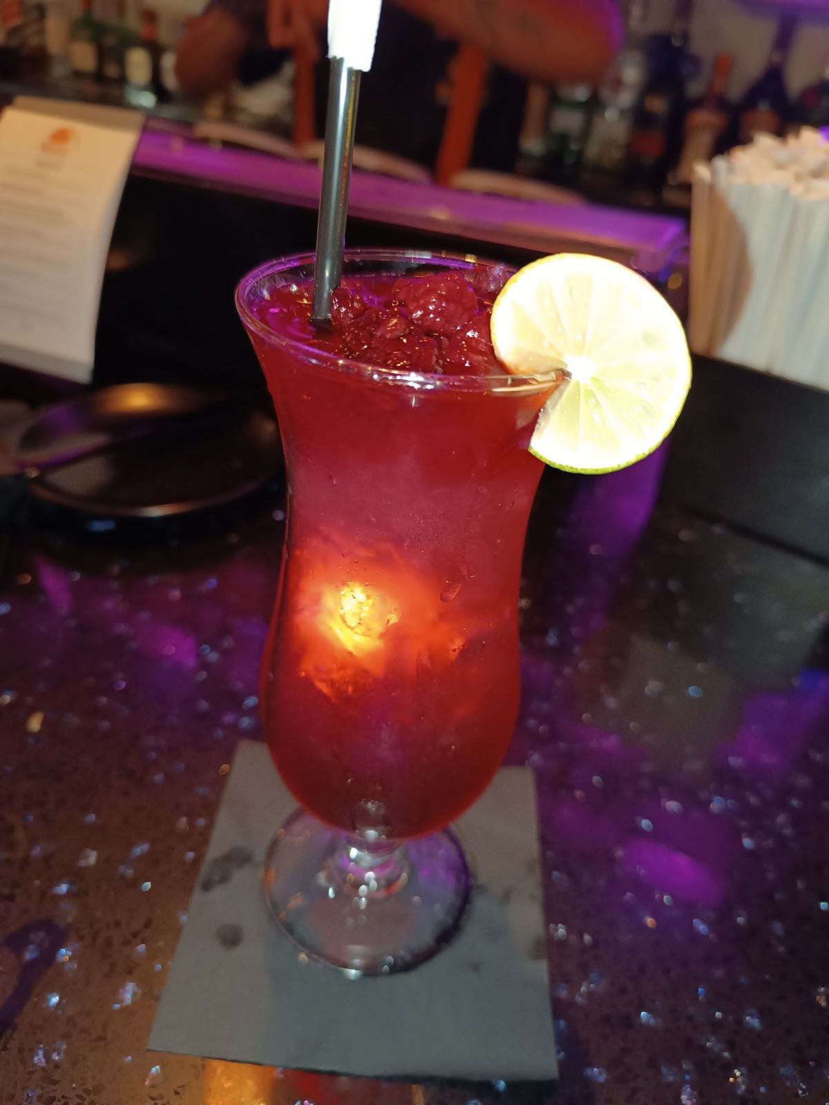 A red pisco cocktail with lime at the neon-lit bar