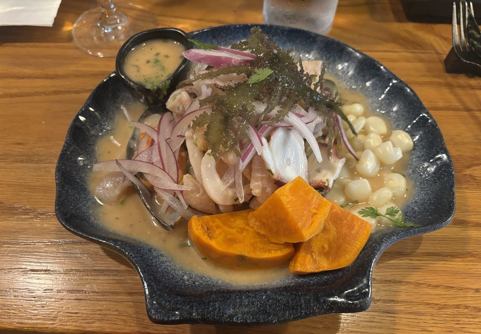 Ceviche mixto on a slate shell plate with choclo, sweet potato and leche de tigre
